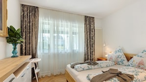 A bedroom with a bed, bedside table, chair, and curtains. - Apartment 'Reichenau' with Private Terrace, Private Garden and Wi-Fi (Reichenau)