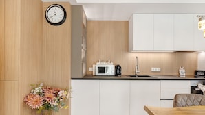 A modern kitchen with white cabinets, a microwave, a coffee maker, and a clock on the wall. - Apartment 'Reichenau' with Private Terrace, Private Garden and Wi-Fi (Reichenau)