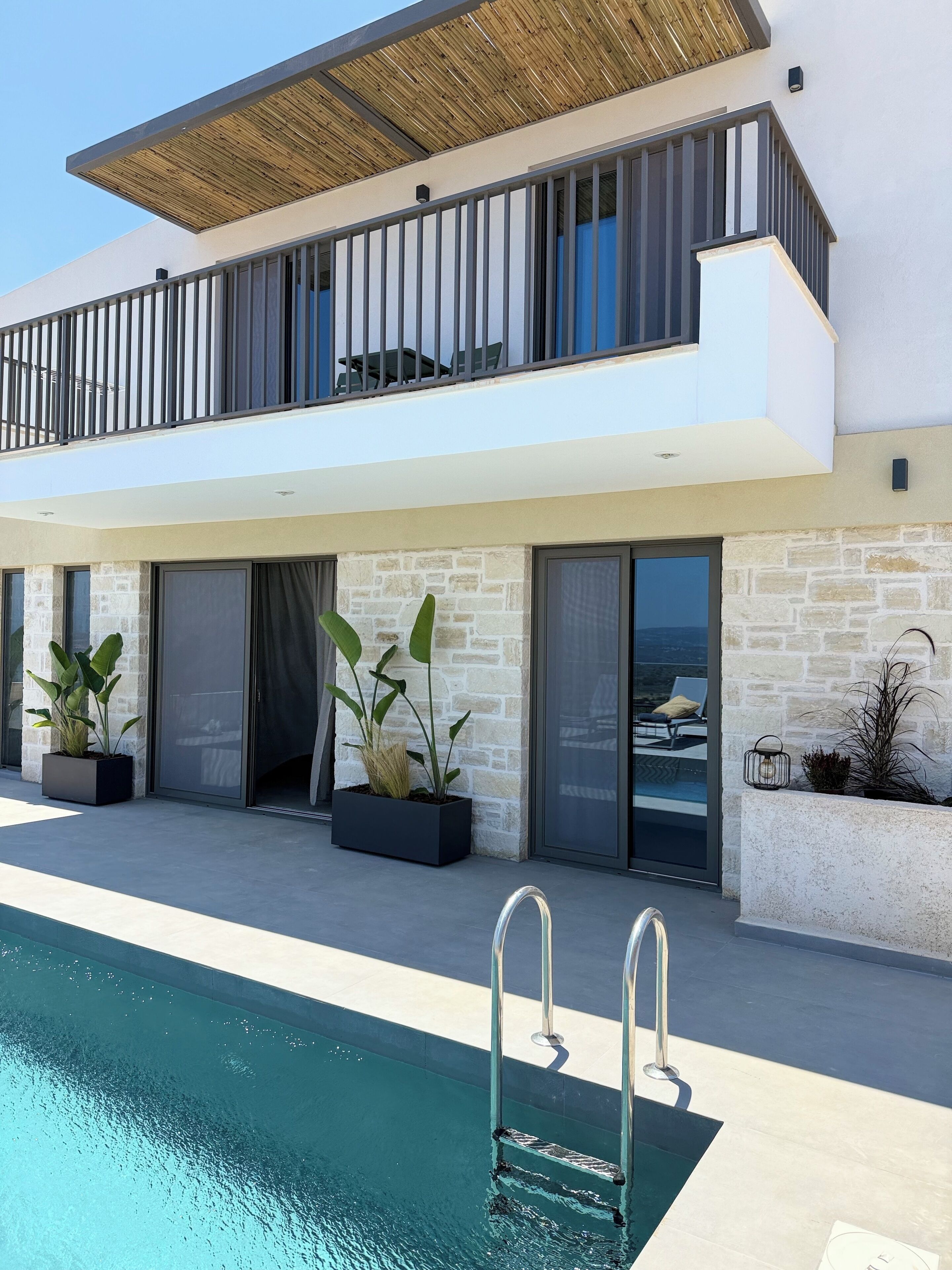 A modern two-story house with a swimming pool, large windows, and outdoor seating.