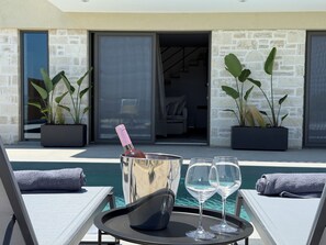 A poolside area with lounge chairs, a tray with a bottle and glasses, and potted plants. - Sunrise Village Aptera Private Pool Villa No1 - Horizon (F477+79, Souda)