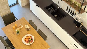 Una cocina moderna con una mesa de comedor de madera, un lavamanos negro y una variedad de utensilios y electrodomésticos.