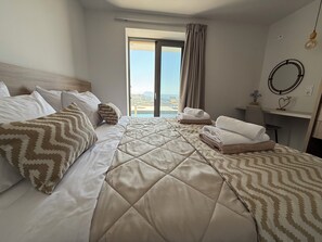 A hotel room with a bed, a desk, a chair, and a view of the outdoors. - Sunrise Village Aptera Private Pool Villa No1 - Horizon (F477+79, Souda)