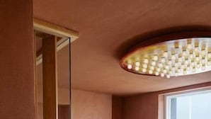 Ein mehrgeschossiges Interieur mit Glastrennwand, einem großen Fenster mit Aussicht und einer außergewöhnlichen Deckenleuchte.