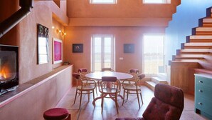Ein gemütliches Wohnzimmer mit Kamin, Esstisch und einer Treppe.