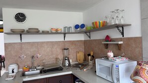 A kitchen with a microwave, sink, and various kitchen utensils. - Charming & Cozy Suite in Quito with Great Location (Quito)