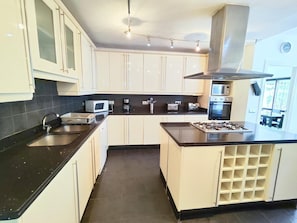 Eine moderne Küche mit weißen Schränken, einer schwarzen Arbeitsplatte, einem Gasherd, einem Backofen, einer Mikrowelle und einer Kaffeemaschine.