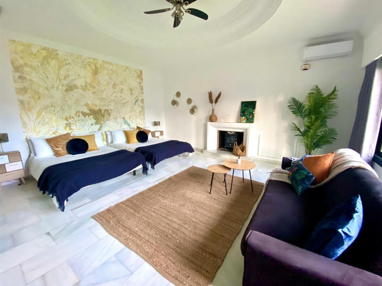 Ein modernes Schlafzimmer mit zwei Betten, einem Kamin, einem Deckenventilator und einem großen abstrakten Gemälde.