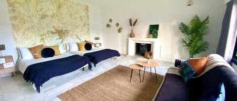 Ein modernes Schlafzimmer mit zwei Betten, einem Kamin, einem Deckenventilator und einem großen abstrakten Gemälde.