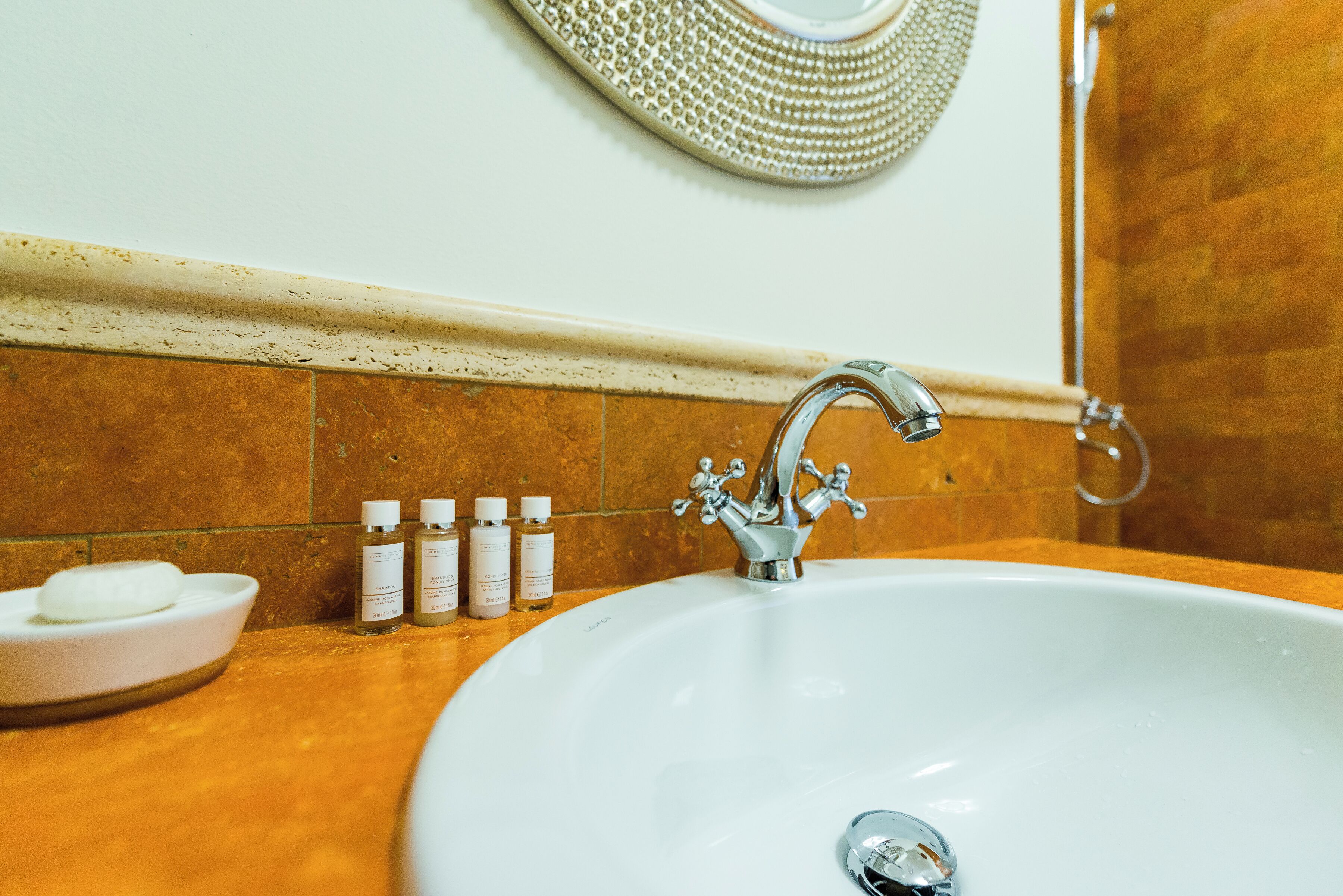 Un bagno con un lavandino bianco, uno specchio e un porta asciugamani.