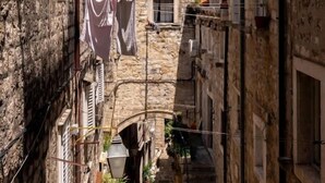 A narrow street with stone buildings, a tiled roof, and laundry hanging outside. - Dominus Rooms  (Dubrovnik)