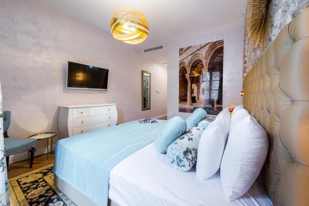 Een slaapkamer met een bed, een televisie, een dressoir en uitzicht op een binnenruimte.