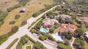 A residential area with houses, a swimming pool, and a road. - Villa Camilla: Private Pool & BBQ, Panoramic Garden Near Le Saline beach (Punta de Su Turrione)