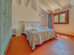 Ein Schlafzimmer mit Bett, Nachttisch, Kleiderschrank und einem Fenster mit Vorhängen.
