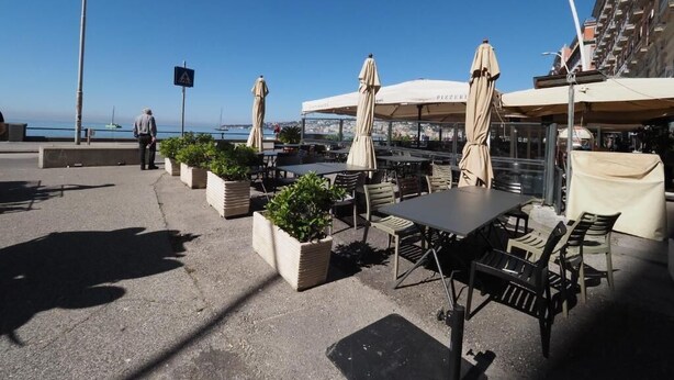 An outdoor seating area with tables and chairs, potted plants, and umbrellas. - L' Angolo sul Mare (Naples)