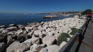 A rocky waterfront with a clear view of the sea and distant cityscape. - L' Angolo sul Mare (Naples)