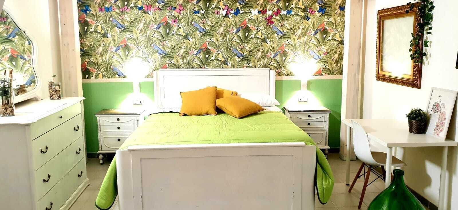 Un dormitorio con una cama, dos mesitas de noche, un aparador, un escritorio y una silla.