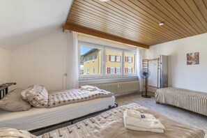 Ein Schlafzimmer mit einem Bett, einem Nachttisch, einem Heizkörper, einem Fenster und einem Wandventilator.