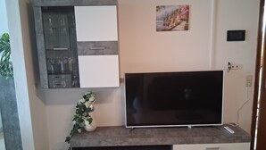 Un téléviseur à écran plat fixé sur un meuble gris, avec un cadre photo au-dessus.