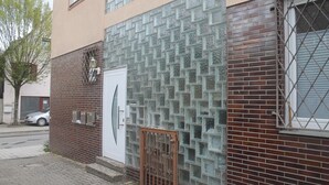 Un edificio con fachada de ladrillo, pared de bloques de vidrio y una reja de metal, con un coche estacionado.