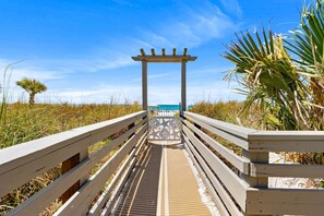 A wooden boardwalk leading to a beach with a pergola structure. - Coastal Escape - Beachfront Studio with Gulf Views (Panama City Beach)