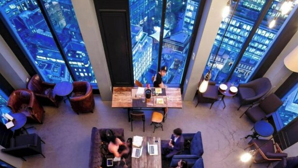 Eine moderne Lounge mit Blick auf die Stadt, bequeme Sitzgelegenheiten und ein zentraler Tisch.