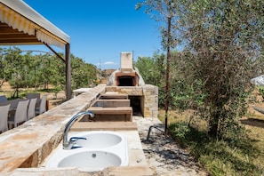 An outdoor kitchen area with a stone sink, wooden steps, and a pizza oven. - Room 'Residenze Uliveto - Residence 14, private terrace and air conditioning (Nardò)