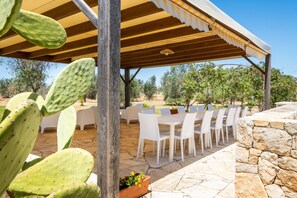 An outdoor patio with white chairs and tables, a wooden pergola, and a cactus plant. - Room 'Residenze Uliveto - Residence 7, private terrace and air conditioning (Nardò)