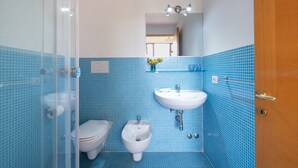 A bathroom with a toilet, bidet, and sink, all with blue-tiled walls and floor. - Room 'Residenze Uliveto - Residenza 8' with Shared Pool, Private Terrace and Air Conditioning (Nardò)