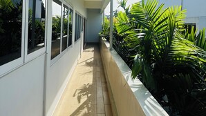 Um corredor com janelas, uma luminária no teto e um vaso com folhagem verde.