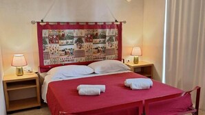 A bed with a red bedspread, two bedside lamps, and a quilted headboard. - Apartment 'Residenze Uliveto - Residenza 10' Private Terrace and Air Conditioning (Nardò)