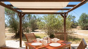 A wooden table set with plates, glasses, and a pitcher under a pergola with a view of trees and a clear sky. - Apartment 'Residenze Uliveto - Residenza 10' with Pool, Private Terrace and Air Conditioning (Nardò)