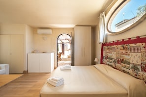 Un dormitorio con cama, armario, escritorio y ventana.