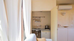 A compact kitchen with a sink, stove, and dishwasher, a white sofa with a beige pillow, and a window with curtains. - Apartment 'Residenze Uliveto - Residenza 10' with Pool, Private Terrace and Air Conditioning (Nardò)