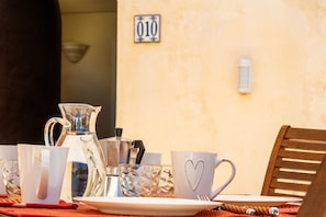Una mesa dispuesta con una cafetera, tazas y una taza con forma de corazón, con un símbolo de número en la pared de fondo.