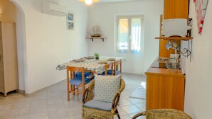 A dining area with a table set for four, surrounded by wicker chairs with blue cushions. - Casa Mimì (Orosei)