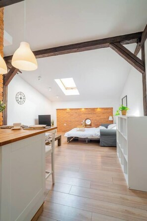 Une chambre de style loft avec une lucarne, un lit, un bureau et un téléviseur.