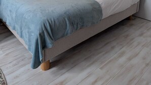 A modern bedroom with a bed, a wall-mounted light, and a wooden floor. - La loge Diane à deux pas du château (Chantilly)