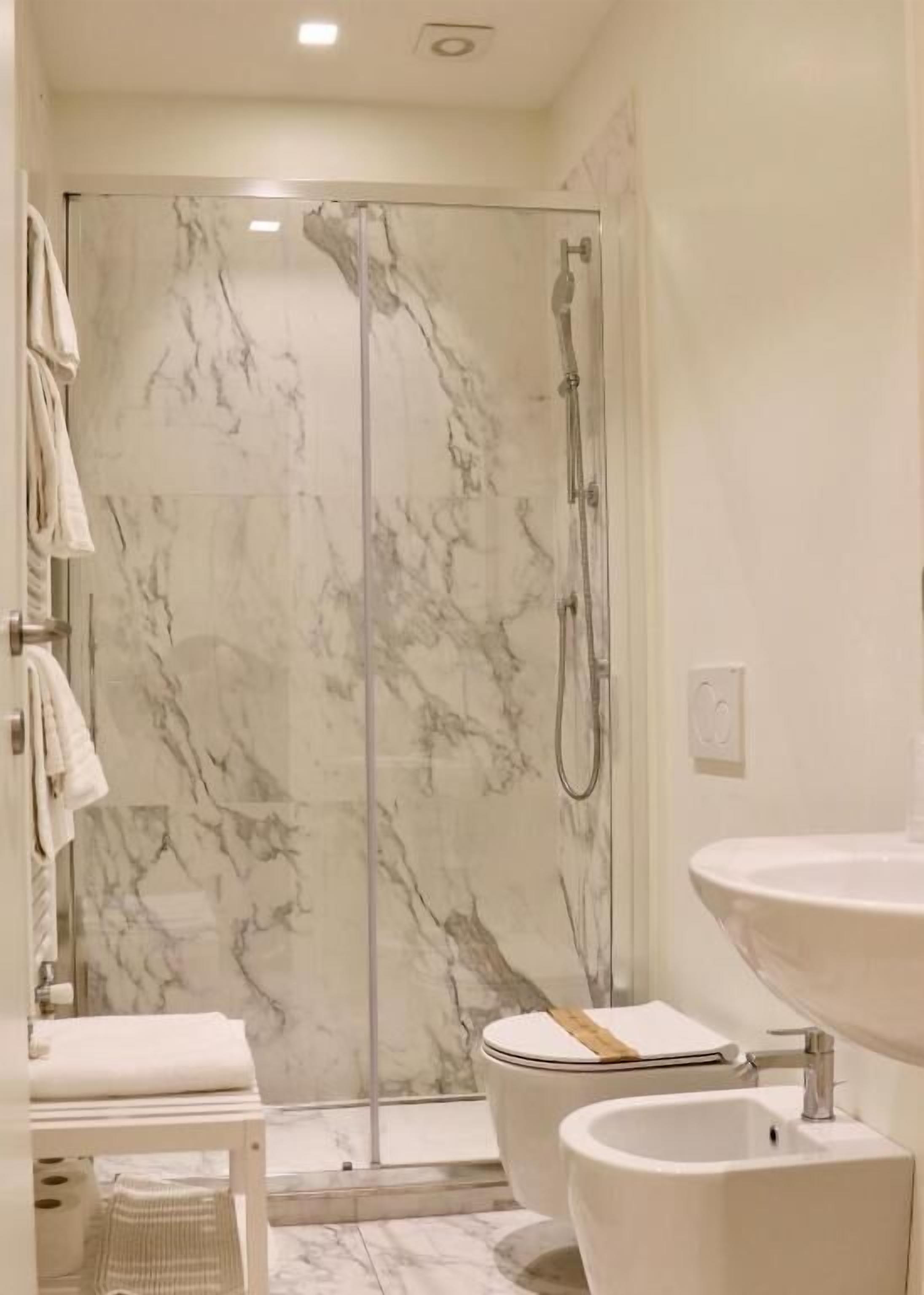 A modern bathroom with a glass-enclosed shower, a white sink, and a toilet.