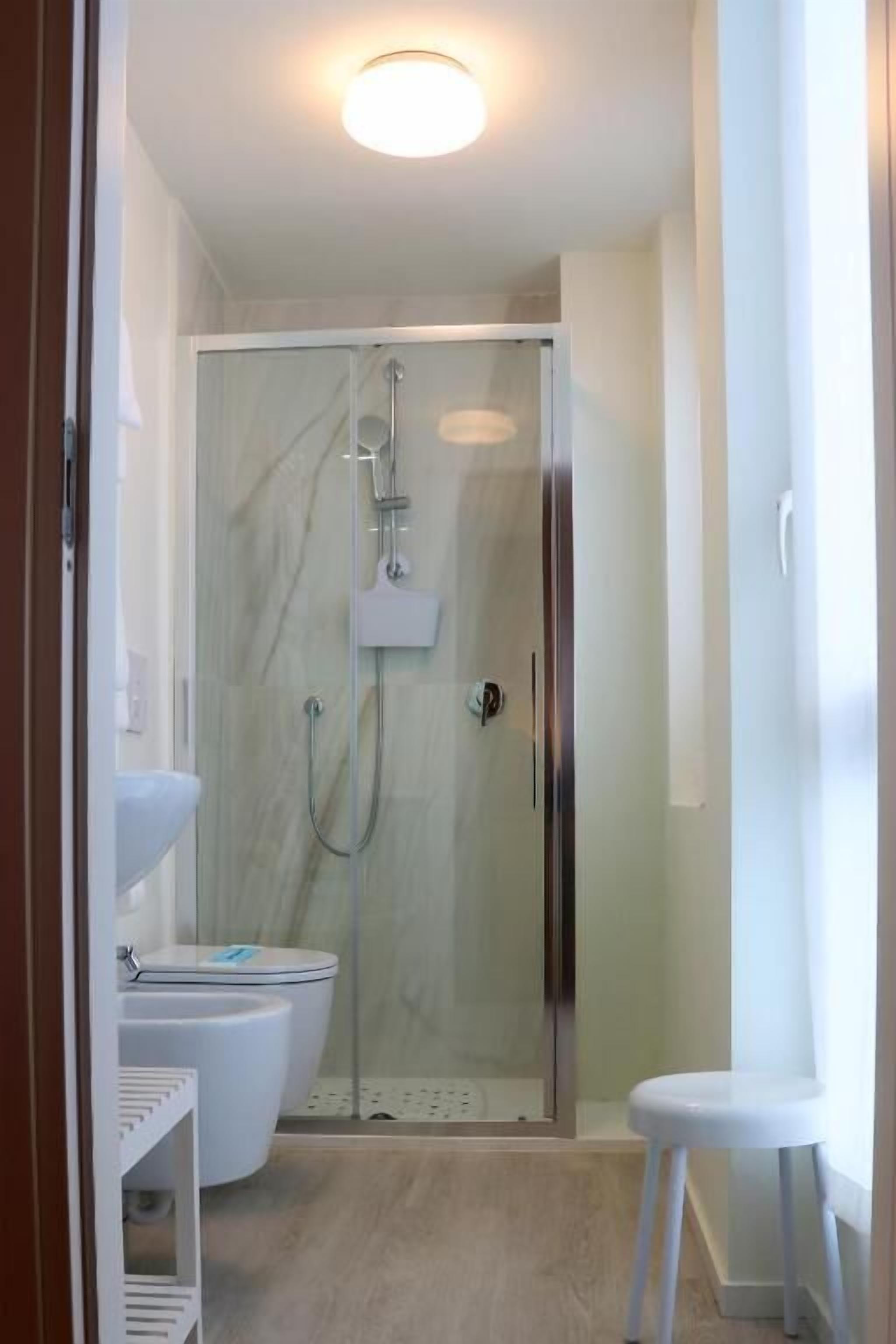 A bathroom with a glass-enclosed shower, a white toilet, and a white sink.