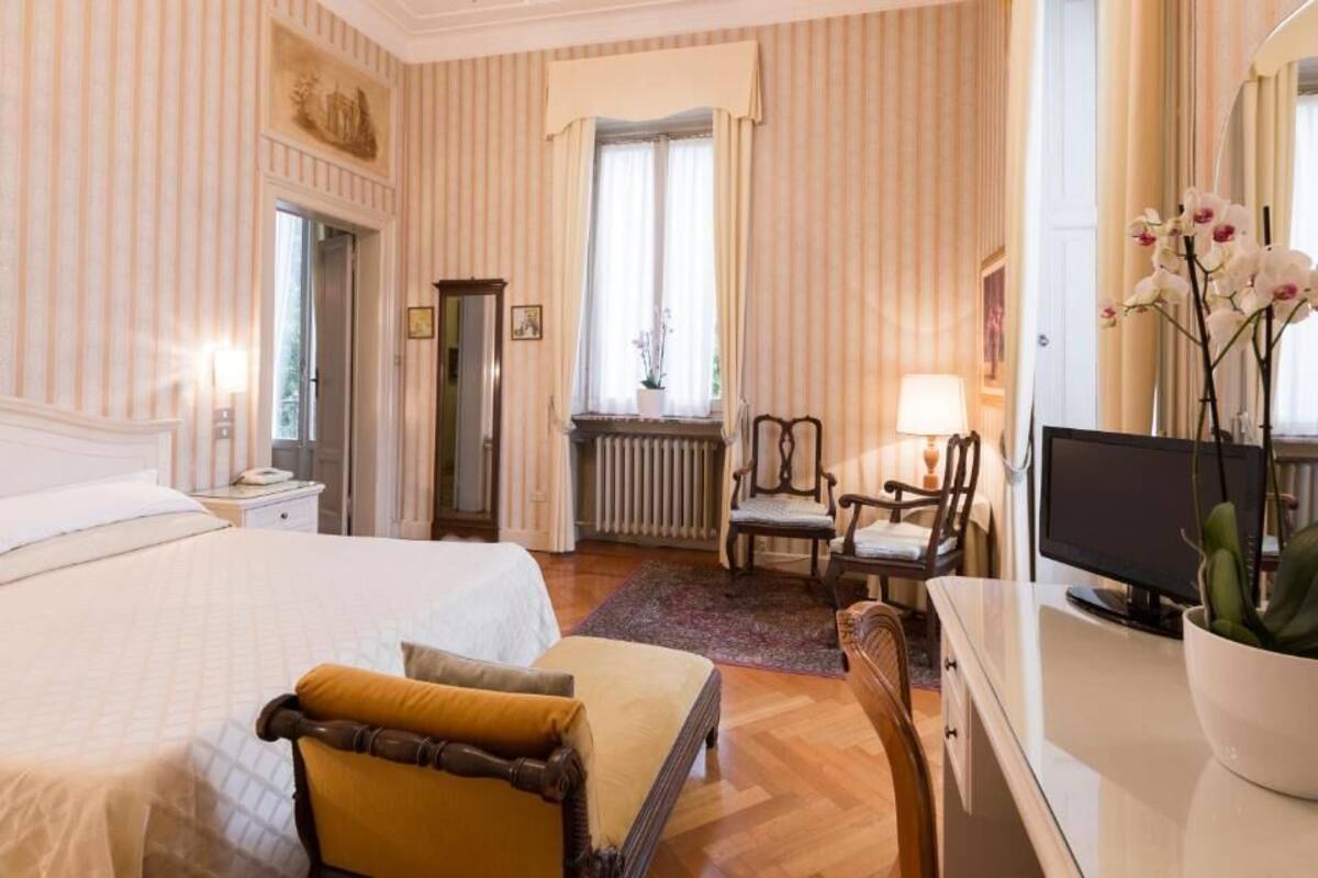A hotel room with a bed, a desk, a chair, a television, and a window with curtains.