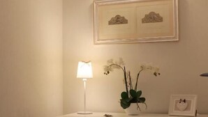 A room with a desk, a chair, a lamp, a wall-mounted light fixture, and a framed picture. - Hotel du Parc (Stresa)