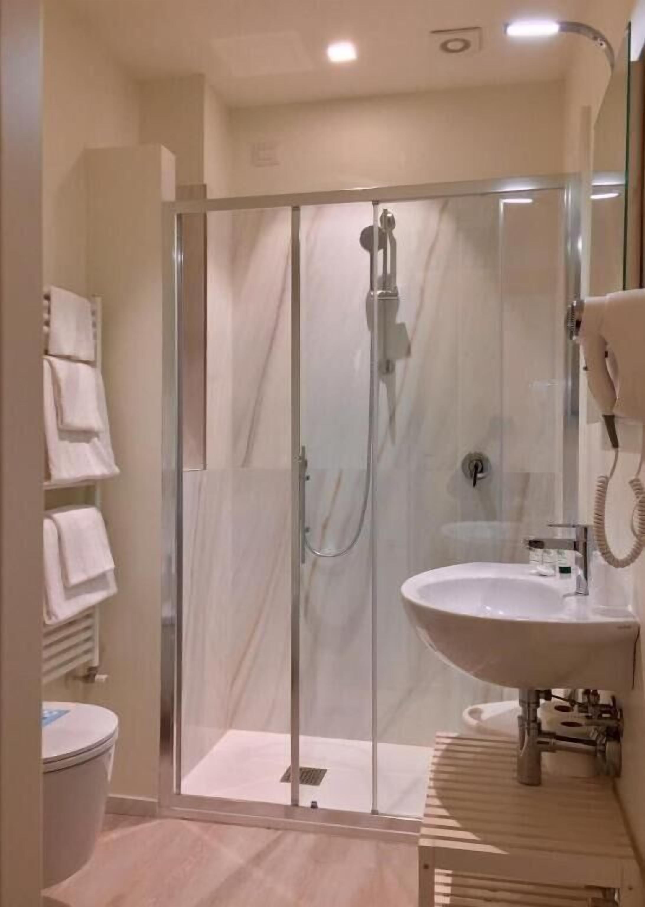 A modern bathroom with a glass-enclosed shower, a white sink, and a towel rack.