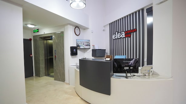 A reception area with a reception desk, a clock, and a wall-mounted sign. - ELEA PREMİUM STAY Zentrale Standard-Doppel-Suite (PAMUKKALE)