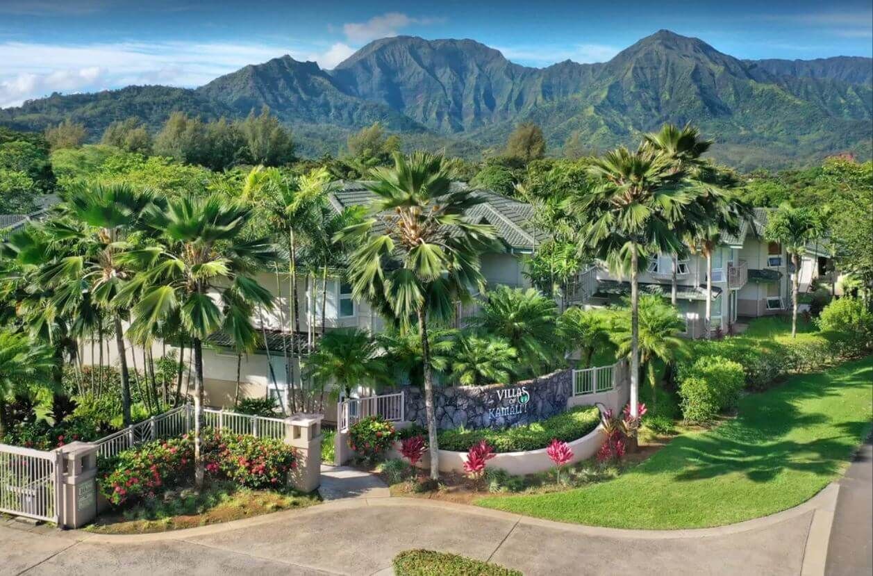 Een resort met villa's, omgeven door weelderige begroeiing en bergen.
