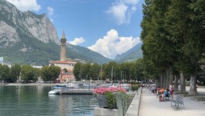 Une vue sur le front de mer, avec une église, des bateaux et une promenade bordée d’arbres et de bancs.