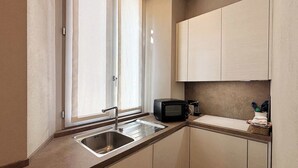 Une cuisine compacte équipée d’un évier, d’un four à micro-ondes et de placards.
