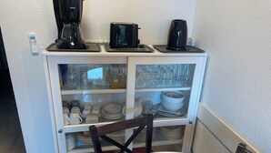 Cozinha com máquina de café, torradeira e chaleira em bancada.