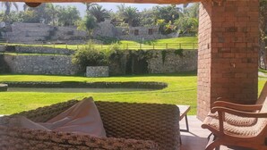 Ein überdachter Außenbereich mit Blick auf einen angelegten Garten und Steinstrukturen.