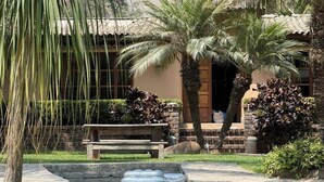Ein Pool mit einer Sitzbank, Palmen und einem Gebäude mit einem Ziegeldach.