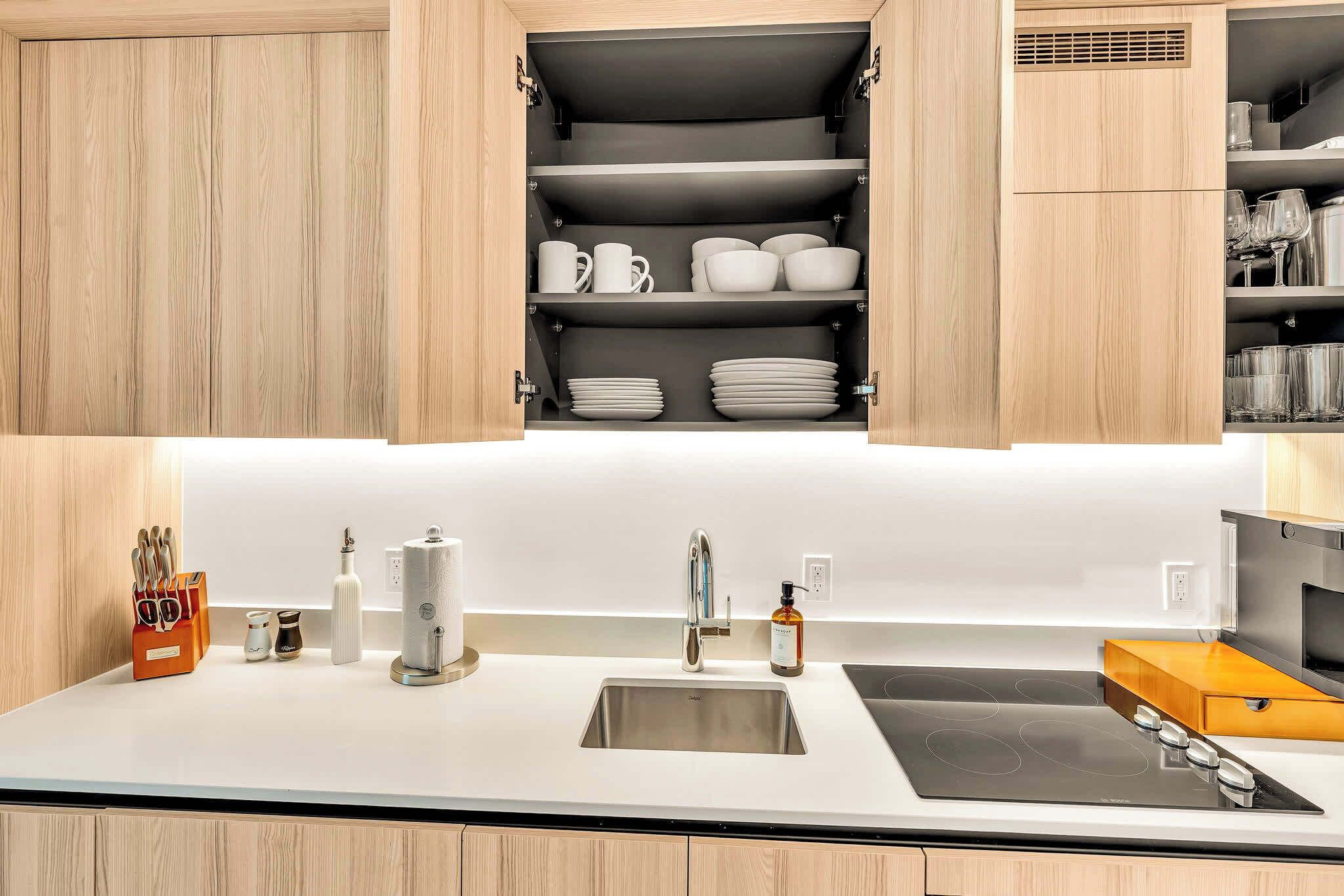 A modern kitchen with a built-in oven, a stainless steel sink, and wooden cabinets.